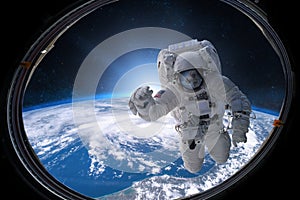 Astronaut in outer space from porthole on background of the Earth