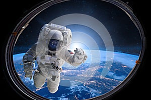 Astronaut in outer space from porthole on background of the Earth. Elements of this image furnished by NASA