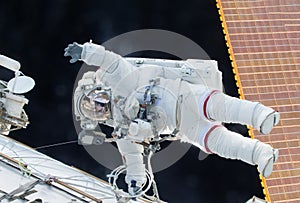 The astronaut in a space suit, in the ISS, lasts a hand in the camera.  Elements of this image were furnished by NASA