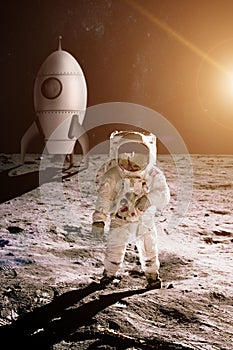 Astronaut is walking on the moon on background of toy rocket.