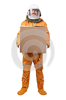 Astronaut wearing orange space suit and space helmet holding in hand blank square cardboard box isolated on white