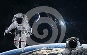 Astronauts in orbit of the planet on a background of blue spiral galaxy somewhere in deep space