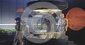 Astronauts and robot examining plant incubator