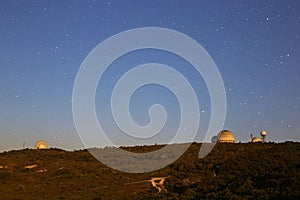 Astronomical observatories on a mountain hill in the evening at sunset with a clear starry sky