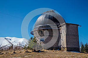 Astronomical observatory with telescope against the background of the blue sky and snowy peaks of the Caucasian mountains