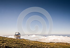 Astronomy observatory on a mountain above the clouds with blue sky. Gran Telescopio Canarias. Telescope dome with beautiful photo