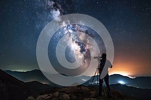 astrophotographer, with camera and tripod, capturing starry night sky above mountain range