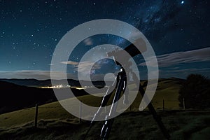 astrophotographer, capturing starry night sky and rolling hills of the countryside