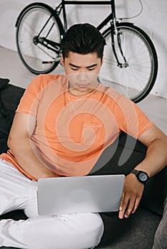 Asuan man using laptop while sitting on sofa at home photo