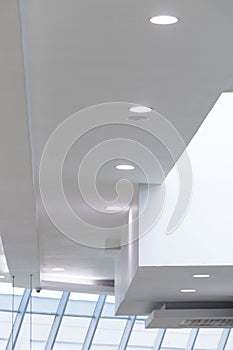 Asymmetric white ceiling with white circular incrustrated lights and window