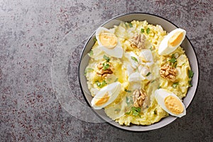 Atascaburras a Delicious Salt Cod and Potato dish with slices of hard boiled egg, walnuts and a dash of oil closeup on the bowl. photo