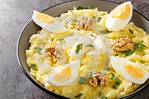 Atascaburras a Delicious Salt Cod and Potato dish with slices of hard boiled egg, walnuts and a dash of oil closeup on the bowl. photo