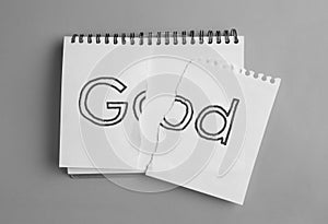 Atheism as religious position. Torn paper with word God in notebook on grey background, top view