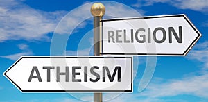 Atheism and religion as different choices in life - pictured as words Atheism, religion on road signs pointing at opposite ways to