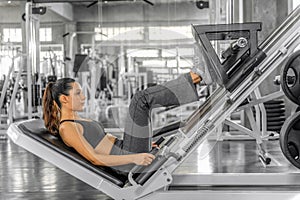 Atheletic woman exercising with lag press machine in gym and fitness club