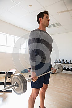 athelte looking away while lifting barbell at gym