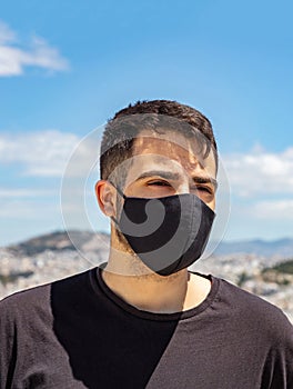 Athens Acropolis, Greece coronavirus days. Young man wearing protective face mask on cityscape background