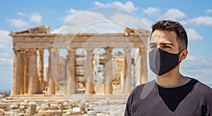 Athens Acropolis, Greece coronavirus days. Young man wearing protective face mask on Parthenon temple and blue sky background