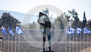 Athens, Greece. Discus thrower bronze statue, rear view. Panathenaic Stadium blur background