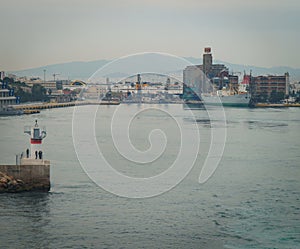 :conseptual shot of the ship that is leaving the port the other ships and the command tower ,in a cloudy day with calm sea