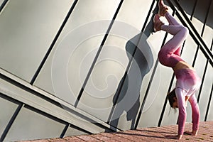 Athetic girl doing handstand against the wall on the street. photo