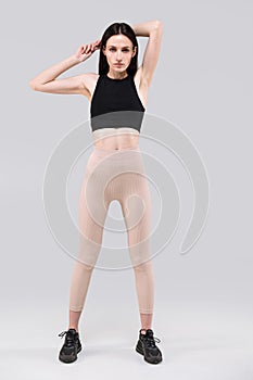 Athlete in activewear standing isolated on gray background holding hands above head