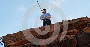 Athlete adjusting his rope on waist while standing on cliff 4k
