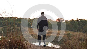 Athlete approaches edge, looks lake, trees countryside in nature