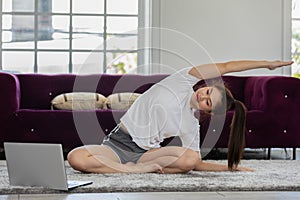 Athlete Asian woman looking laptop practice yoga online course at home