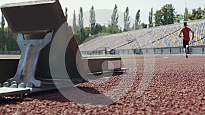 Athlete beginning to run from starting blocks at competition, slow-motion