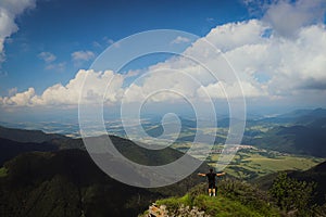 Athlete in a black t-shirt sits on top of Mala fatra mountain. Hiker walks along ridges of Lesser Fatra in the Slovak mountains.