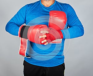 athlete in blue clothes, hands are rewound with red textile bandage