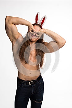 Athlete bodybuilder shirtless with long hair posing with a rabbit-like ears