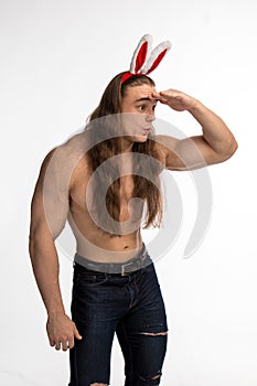 Athlete bodybuilder shirtless with long hair posing with a rabbit-like ears