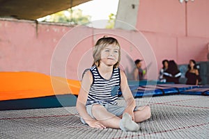 Athlete Caucasian boy sitting on trampoline after training. child is engaged in trampolining on professional trampoline outside.