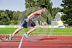 Athlete on cinder track of sports facility starts to sprint