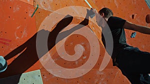 An athlete-climber performs a jump by grabbing a climbing wall with his hand
