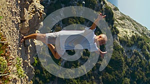 Athlete concentrating yoga asana at sea cliff edge. Serene man exercise vertical