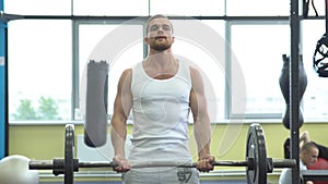 Athlete doing exercise for biceps with barbell. young muscular man trains at the gym. crossfit training