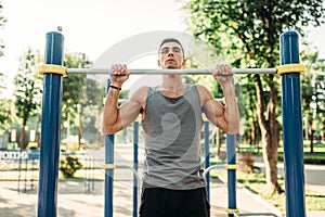 Athlete doing exercise on horizontal bar outdoor