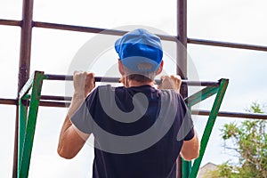 Athlete doing pull-up on horizontal bar. Male sportsman doing fitness exercises on playground outdoor during work break