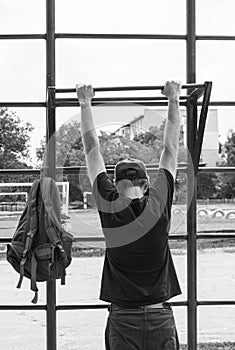 Athlete doing pull-up on horizontal bar. Male sportsman doing fitness exercises on playground outdoor during work break