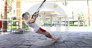 Athlete doing pull-ups and using fitness belt, strengthen strength of outdoor workout