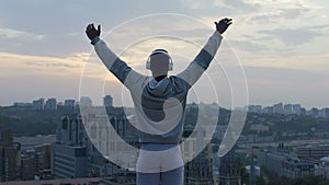 Athlete doing yoga at edge of roof, receiving charge of vivacity and relaxation