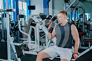 Athlete drinking from a shaker bottle in the background of the gym