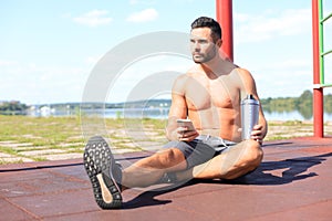 Athlete drinking water and relaxing after intense workout outdoors