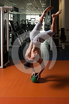 Athlete Exercising Handstand Push-Ups On Ball In Gym