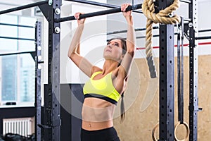 Athlete fit woman performing pull ups in a bar exercising at gym.