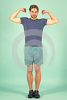 Athlete flex muscles with biceps. Fashion sportsman in blue sport uniform. Bearded man with stylish hair. Power and