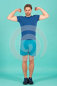 Athlete flex muscles with biceps. Fashion sportsman in blue sport uniform. Bearded man with stylish hair. Power and fitness concep